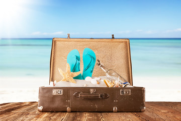 Old suitcase with accessories on beach