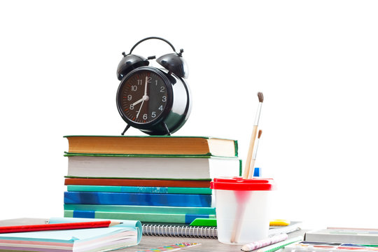 books and an alarm clock on a wooden table on a white background