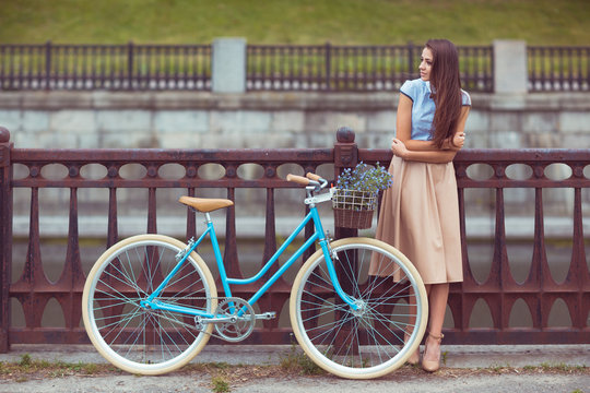 Young beautiful, elegantly dressed woman with bicycle, summer an
