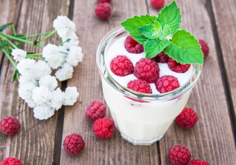 Glass of yogurt with raspberry on wooden table