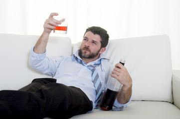 drunk Businessman drinking whiskey lying on couch at home