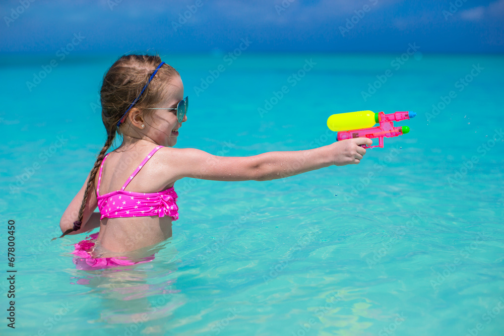 Wall mural Happy little girl playing at beach during caribbean vacation