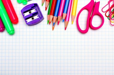 Colorful school supplies border over graphing paper