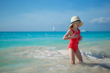 Happy little girl in hat on beach during summer vacation