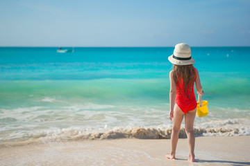 Fototapeta na wymiar Happy little girl in hat on beach during summer vacation