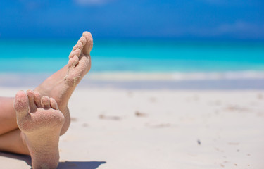 Close up of female feet on white sandy beach