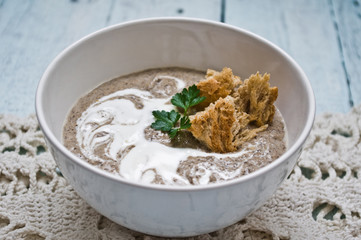 Bowl with cream of mushroom soup on a wooden table