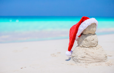 Little sandy snowman with red Santa Hat on white Caribbean beach