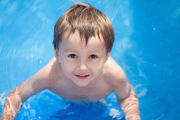 Fototapeta na wymiar Cute boy in a pool, photographed from above