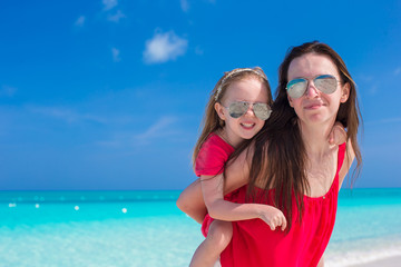 Young mother and little daughter have fun at tropical beach