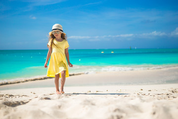 Happy little girl in hat on beach during summer vacation