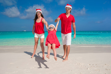 Happy family in Christmas Hats having fun on white beach