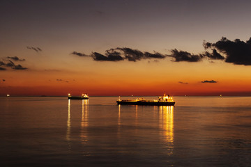 Naklejka premium Cargo ship underway at sunset