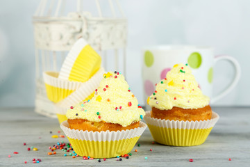 Tasty cup cakes with cream on grey wooden table