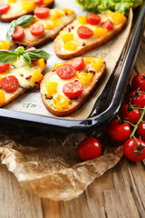 Tasty bruschetta with tomatoes on pan, on old wooden table
