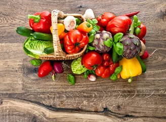 vegetables and herbs in basket on wooden background