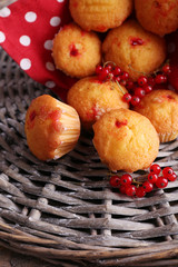 Tasty muffins with red currant on wicker mat background