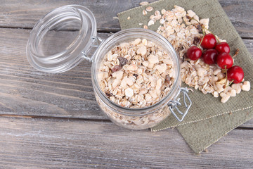 Homemade granola in glass jar, on color wooden background