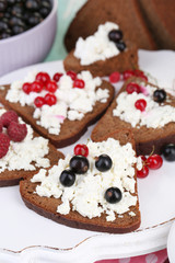 Bread with cottage cheese and berries on wooden tray close-up