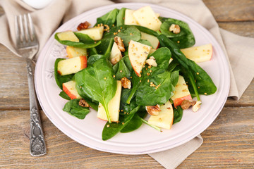 Green salad with apples, walnuts and cheese on wooden