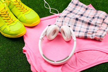 Sport clothes, shoes and headphones on green grass background