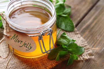 Homemade mint jelly in glass jar, on wooden background