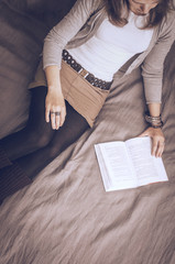 Fototapeta premium gray-brown tones background girl is lying on the couch reading a