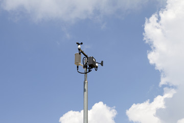 Weather station mast against blue cloudy sky