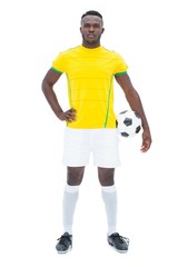Football player in yellow standing with the ball