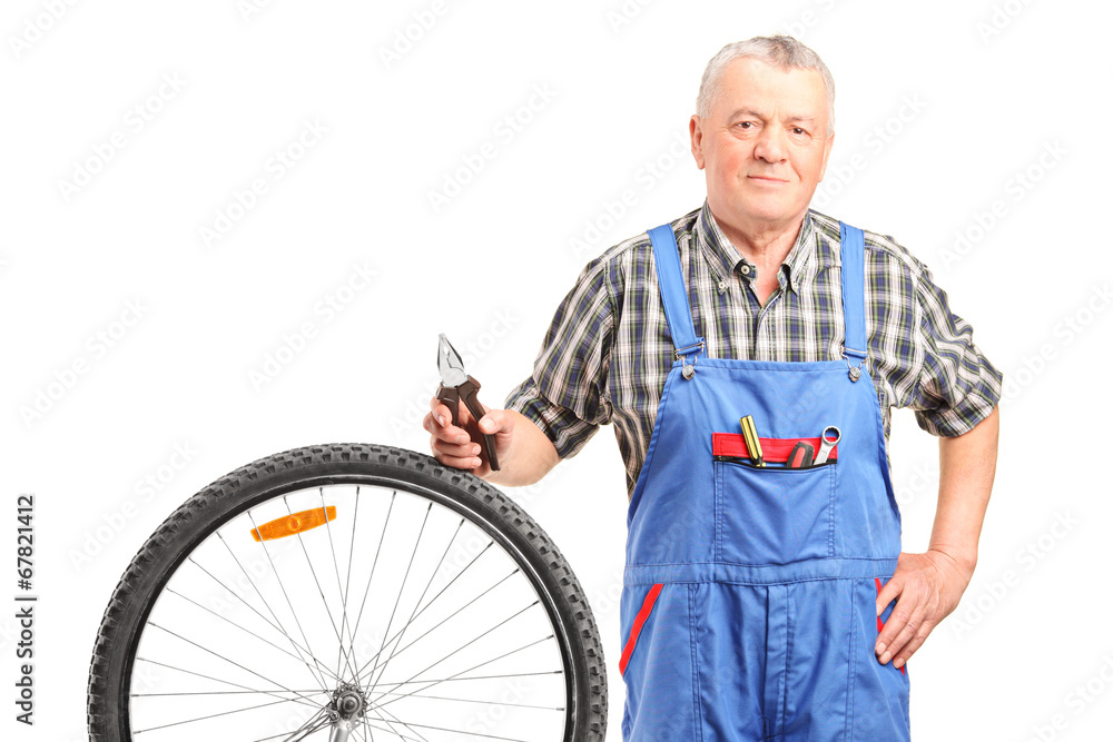 Poster Mature mechanic standing by a bicycle wheel