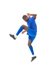 Football player in blue kicking and jumping