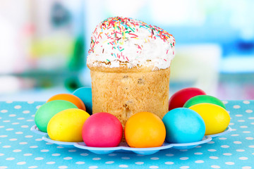 Sweet Easter cakes with colorful eggs on table in room