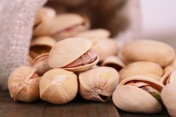 Pistachio nuts in sackcloth bag on table close up