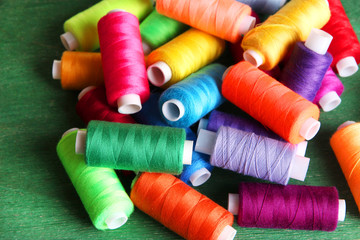 Multicolor sewing threads on wooden background