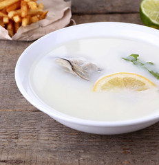 Tasty soup with oysters on wooden table