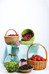 Fresh berries in baskets on white wall background