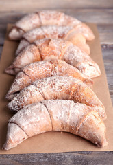 Tasty bagels with sugar powder, on wooden background