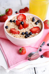 Tasty oatmeal with berries on table close-up