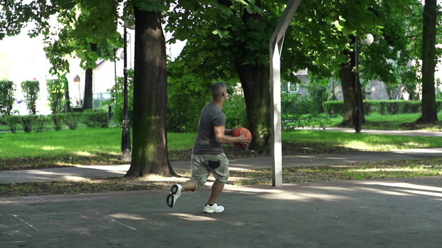 Man playing basketball on court in park, super slow motion, 