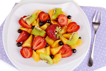 Fresh fruits salad on plate on napkin close up