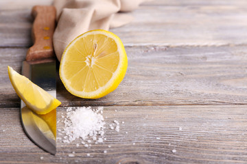 Still life with fresh lemon, knife and salt on old wooden table