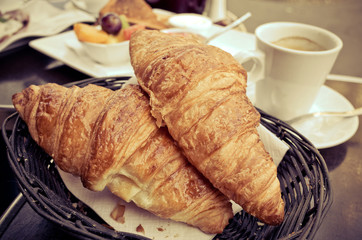 coffee and croissants in a basket on table