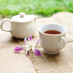 cup of black coffee  with purple orchid and burlap cloth on wood
