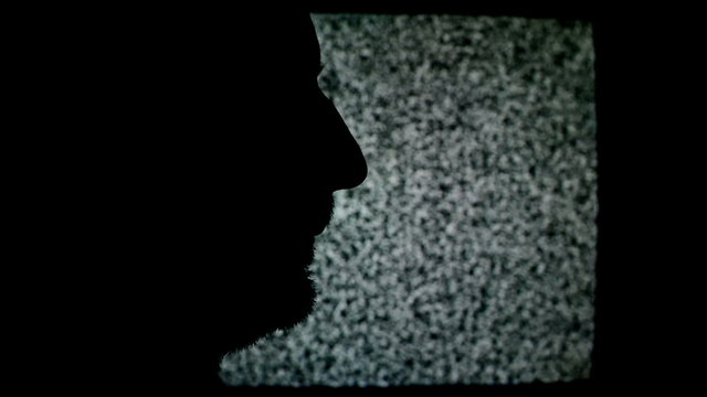 Unshaven man profile silhouette in front of static TV noise