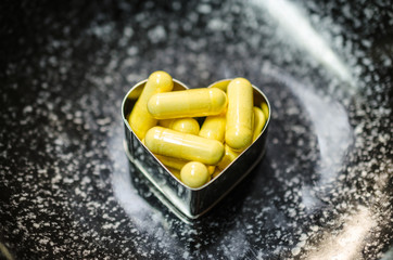 yellow food supplemnet CoQ10 (Co-enzyme Q10) capsules in two hea