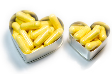 yellow food supplemnet CoQ10 (Co-enzyme Q10) capsules in two hea