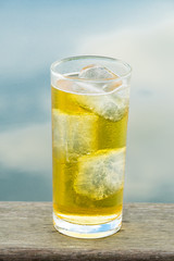 A Glass of beer with ice beside thailand river that reflex the s