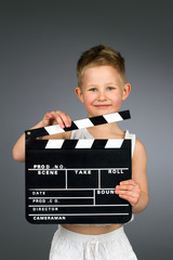 Smiling kid holding movie clapper board.