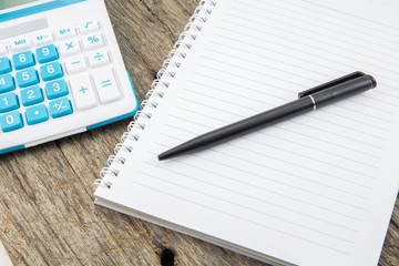 note paper,pen and calculator on wooden table