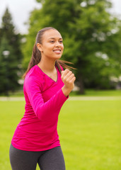 smiling young woman running outdoors